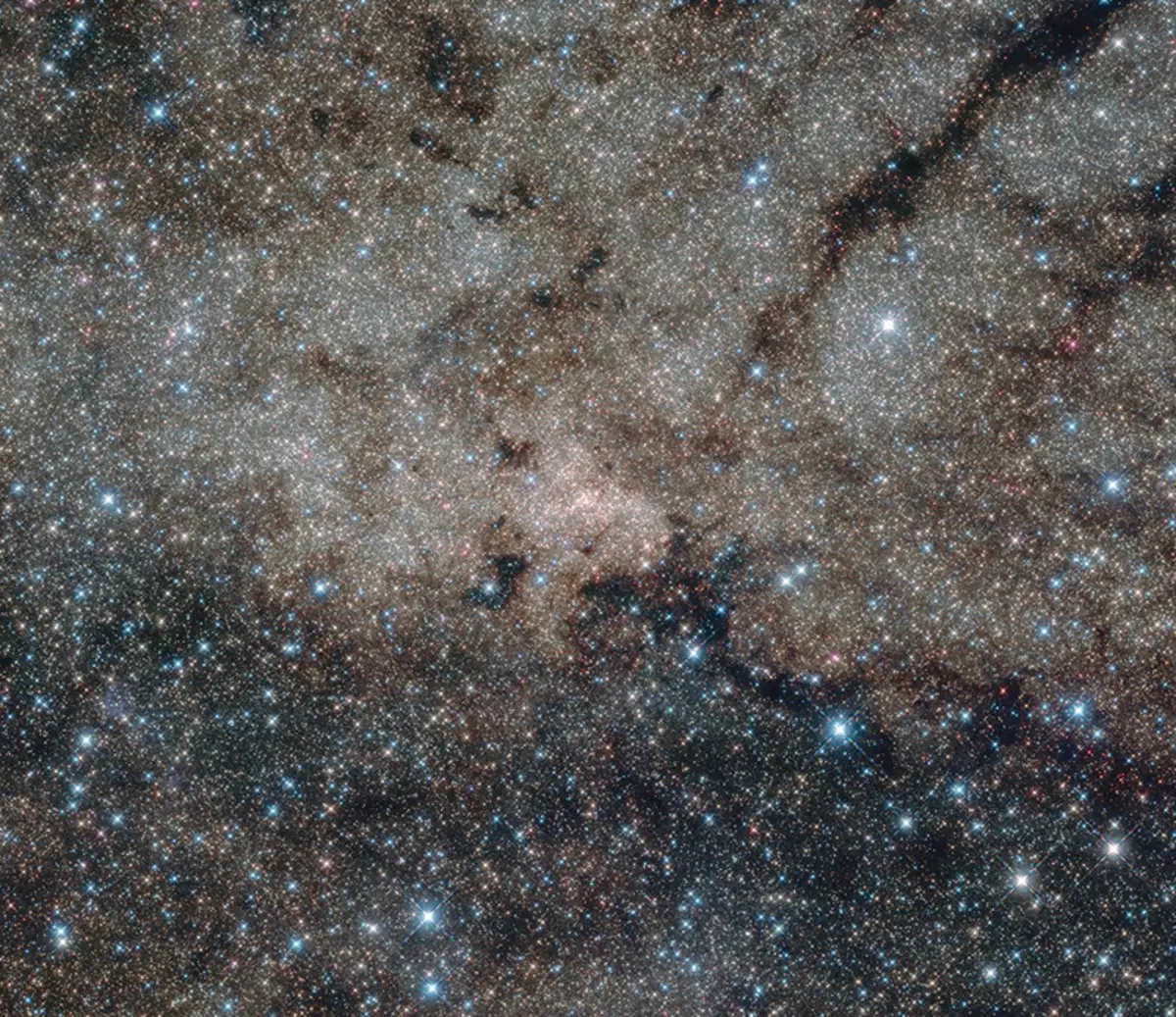 Ĉi tiu transruĝa bildo de la Lakta Vojo, 27 000 lum-jarojn for de la Tero. Uzante la transruĝaj kapabloj de Hubble, astronomoj povis rigardi tra la polvo, kiu kutime kaŝas la vidpunkton de ĉi tiu interesa regiono. En la centro de ĉi tiu nuklea stela areto - kaj ankaŭ en la centro de ĉi tiu bildo - la supraĵa nigra truo situas.