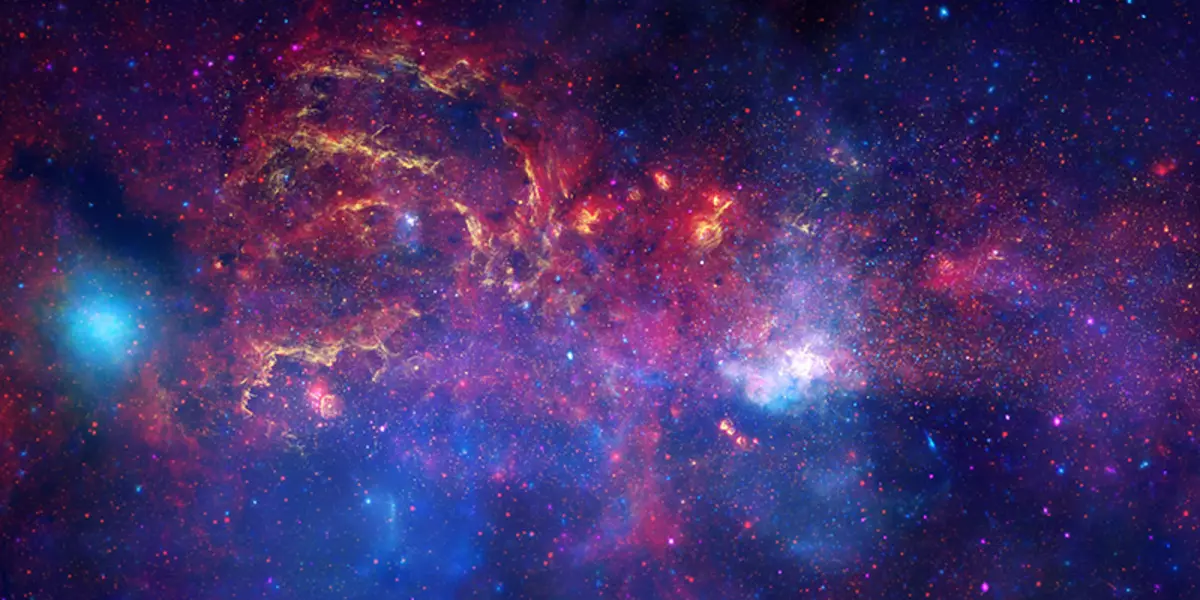 En celebración del Año Internacional de Astronomía 2009, el Telescopio Espacial del Hubble de la NASA / ESA y su compañero Grandes Observatorios: El Telescopio Espacial Spitzer y el Observatorio de Radiografía de Chandra han colaborado para producir una imagen sin precedentes de la región central de nuestra Vía Láctea Galaxy . En esta imagen espectacular, las observaciones que utilizan la luz infrarroja y la luz de rayos X ven a través del polvo oscurecido y revelan la intensa actividad cerca del núcleo galáctico. Tenga en cuenta que el centro de la galaxia se encuentra dentro de la región blanca brillante a la derecha de la derecha y justo debajo de la mitad de la imagen. Todo el ancho de la imagen cubre aproximadamente medio grado, sobre el mismo ancho angular que la luna llena. La contribución de cada telescopio está presente en un color diferente: amarillo representa las observaciones de infrarrojos casi infrarrojos del Hubble. Elimina las regiones energéticas donde las estrellas están naciendo, así como revelan cientos de miles de estrellas. Rojo representa las observaciones infrarrojas de Spitzer. La radiación y los vientos de las estrellas crean nubes brillantes de polvo que exhiben estructuras complejas de glóbulos compactos, esféricos a un filmen largo y fijo. Azul y violeta representan las observaciones de la radiografía de Chandra. Las radiografías son emitidas por el gas calentadas a millones de grados por explosiones estelares y las salidas del agujero negro supermasivo en el centro de la galaxia. La brillante mancha azul en el lado izquierdo es la emisión de un sistema de doble estrella que contiene un sistema de orificio negro que continúa eiter una estrella de neutrones o un agujero negro. Cuando se juntan estas vistas, esta imagen compuesta proporciona una de las vistas más detalladas de nuestro misterioso núcleo de nuestra galaxia.